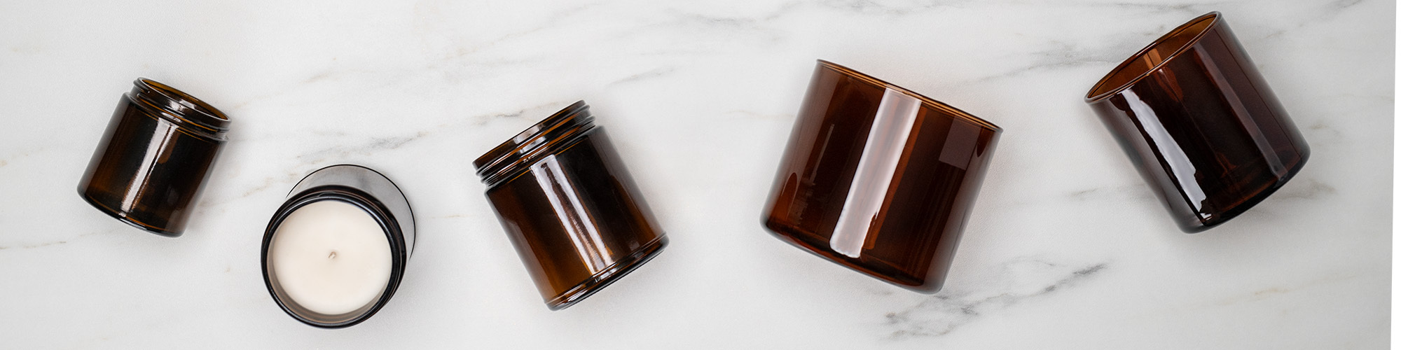 Amber candle containers on marble surface